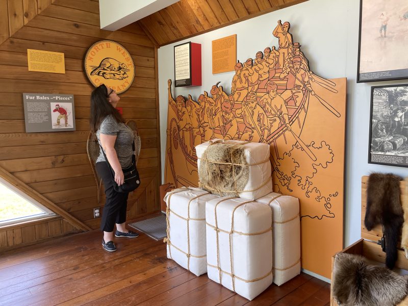 A guest reading about the fur trade inside the HMS Nancy museum